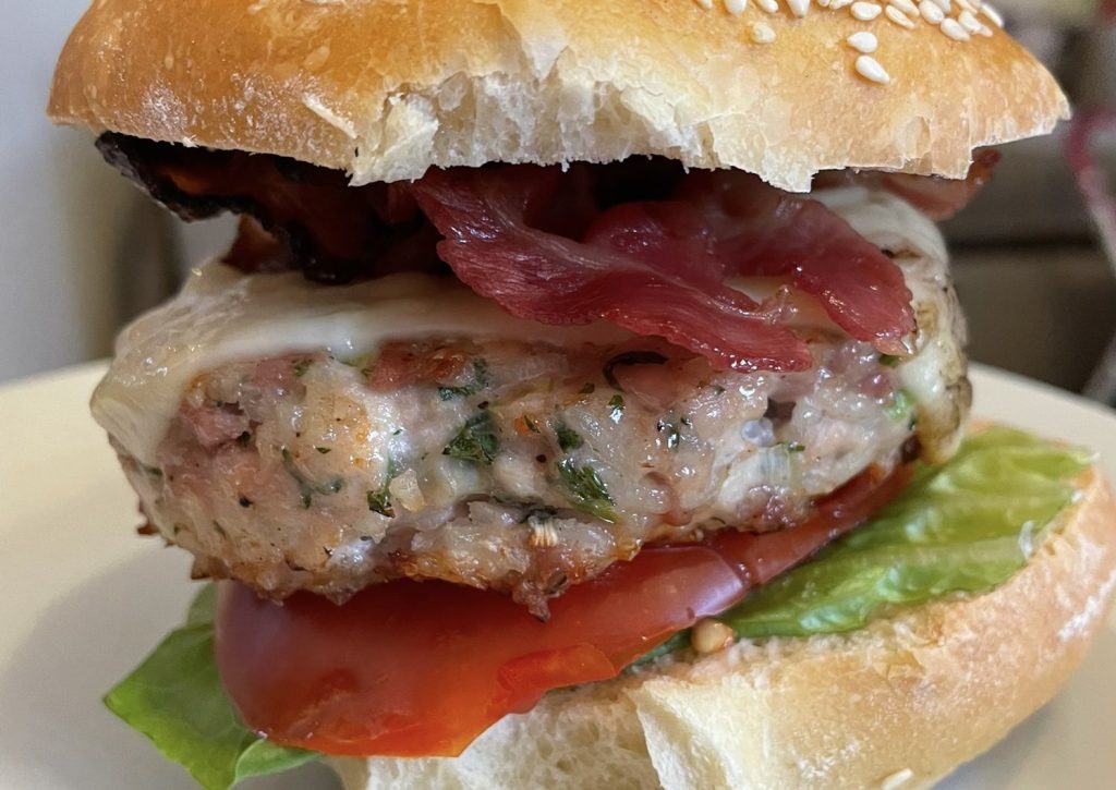 A burger made from chicken and rice in a bread bun with salad.